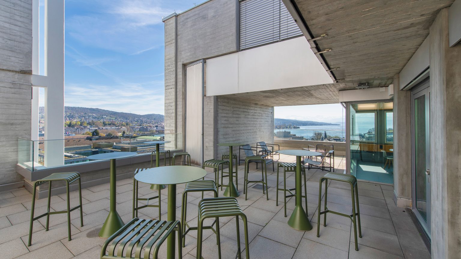 Eine Dachterasse mit Sitzplätzen und den Blick auf Zürich.