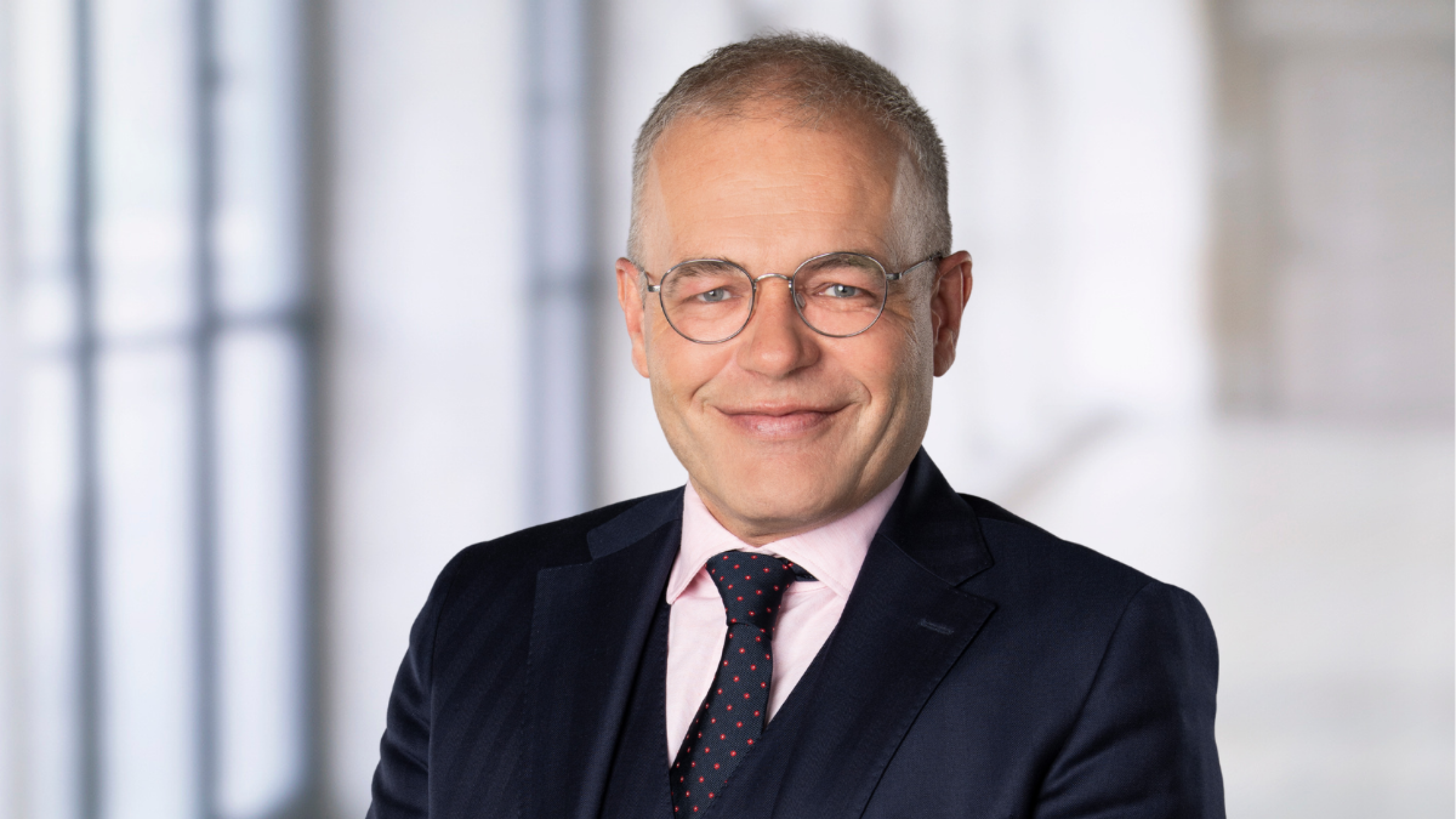 A picture of a man in a suit wearing glasses.