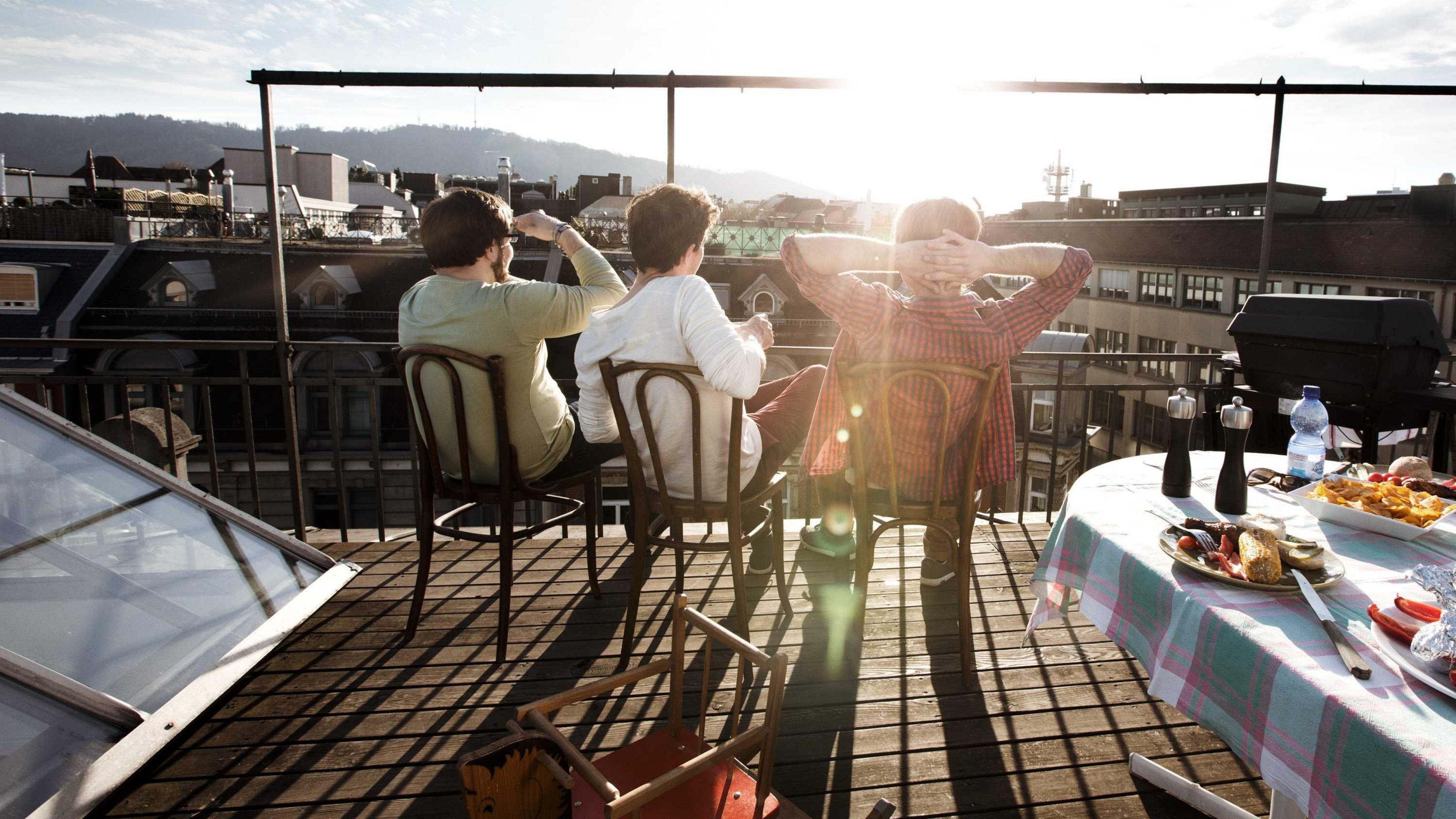 People sitting on a roof terrace and gazing into the distance.