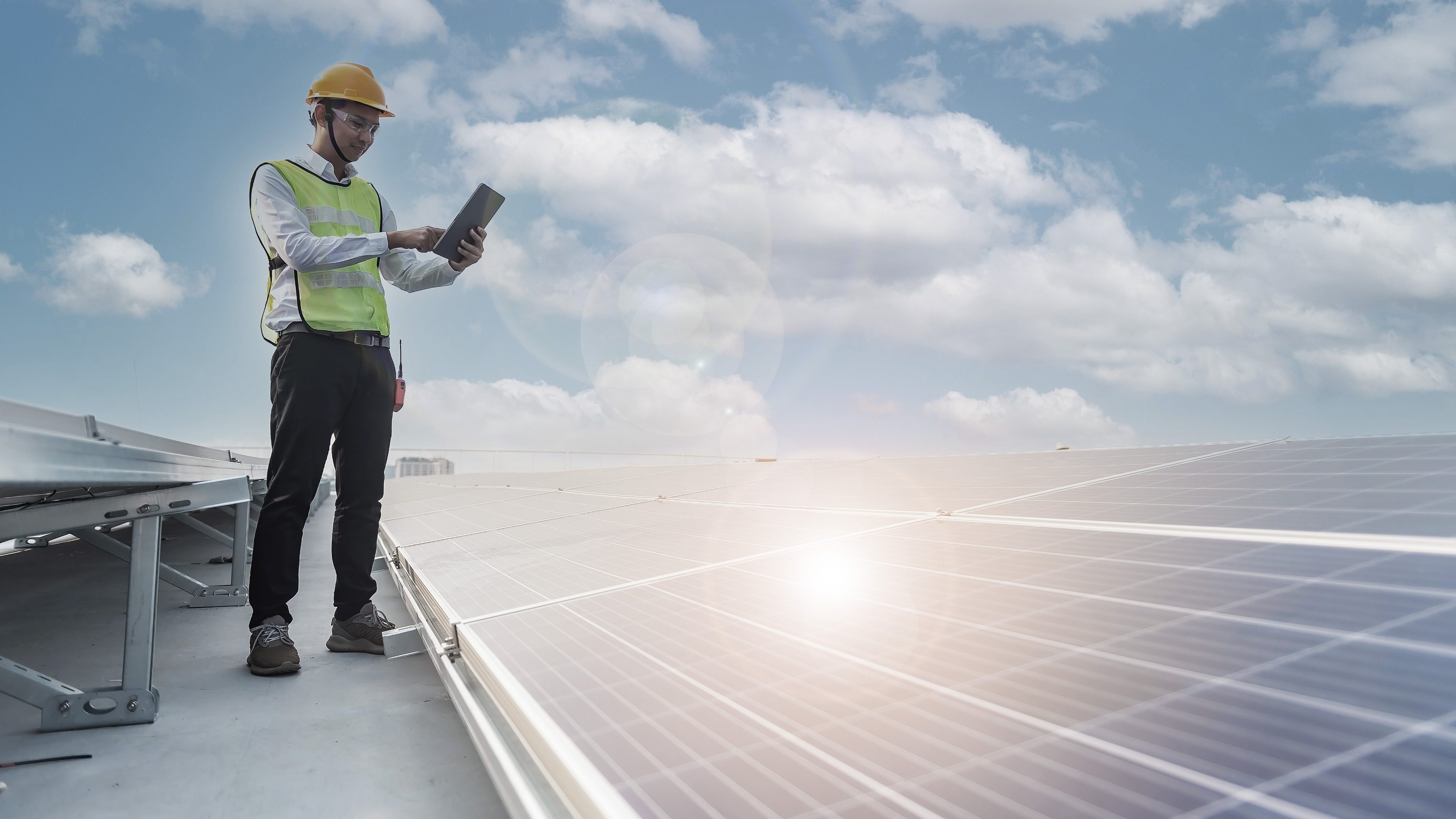 Engineer holding notebook sets the operation of the solar panel on the roof of the building to work at full efficiency.Using solar cells is energy saving. Renewable energy concepts.