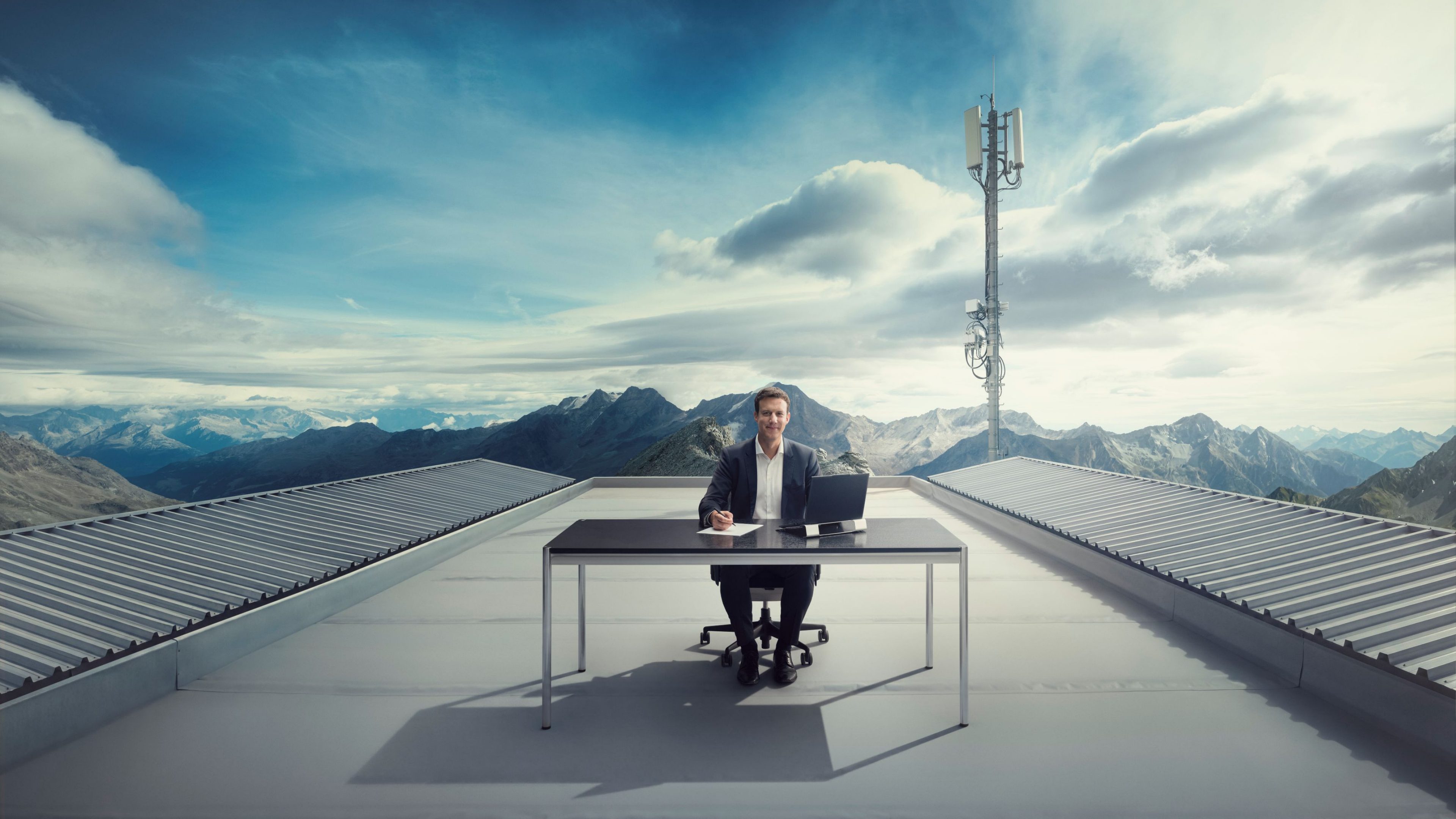 Personne travaillant à un bureau sur un toit avec vue sur les montagnes.