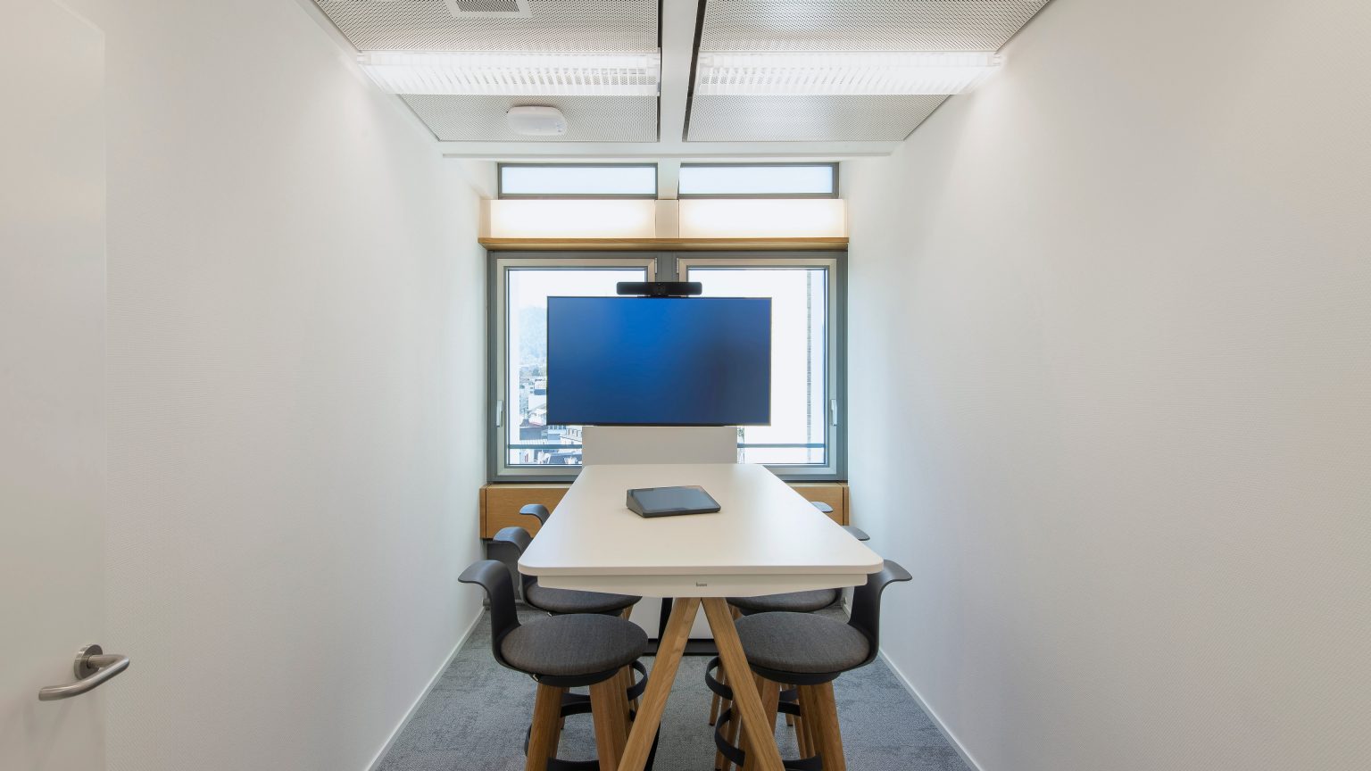 A meeting room with a high table and a screen.