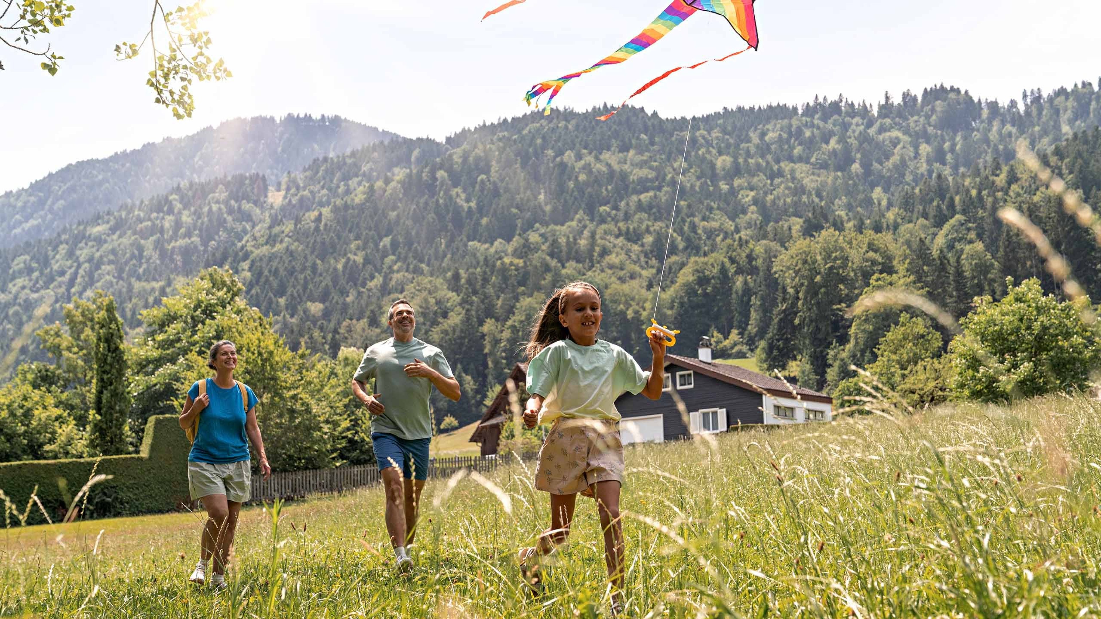 Una famiglia passeggia in un campo mentre la figlia tiene in mano un aquilone.