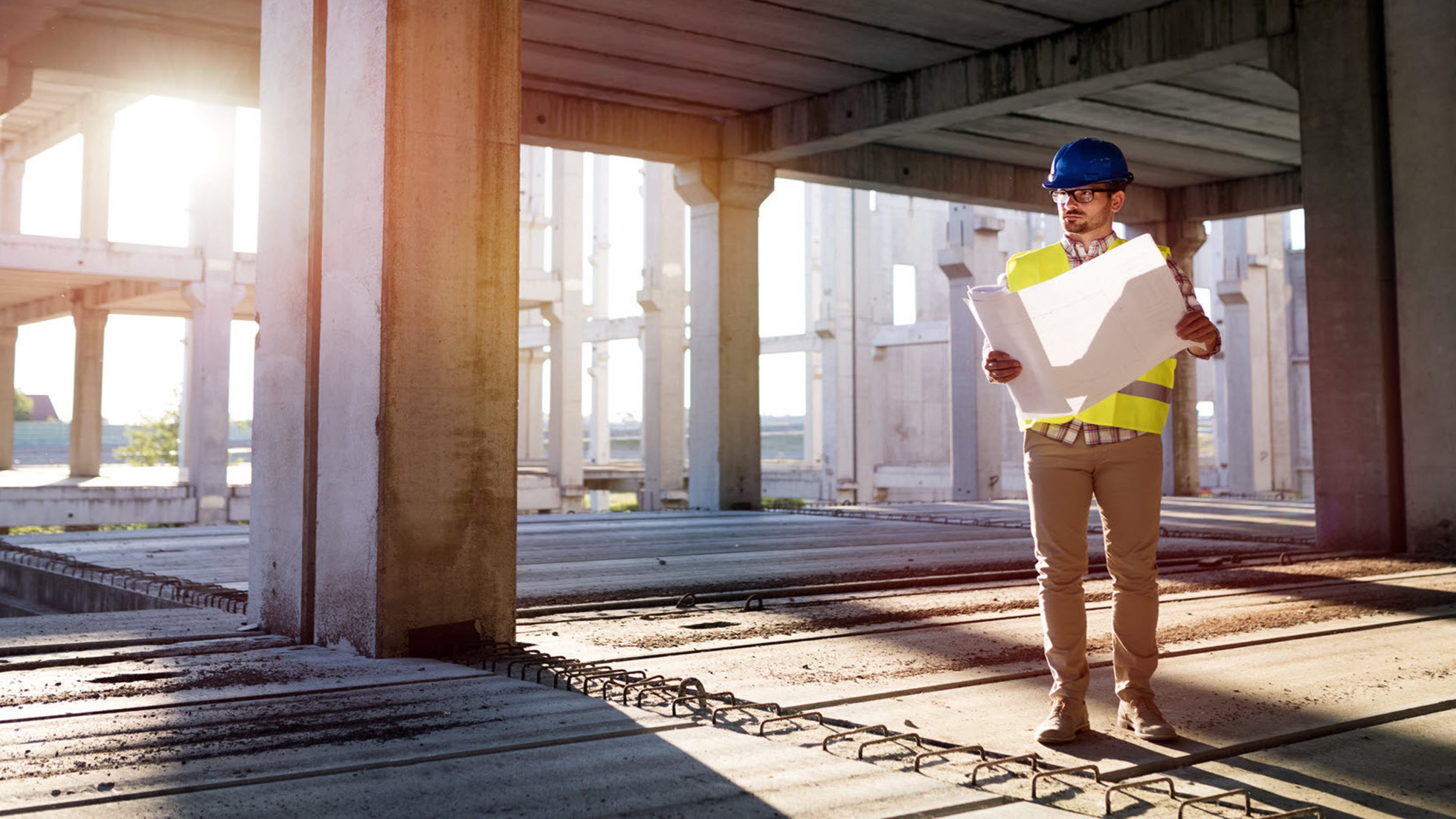A man on a construction site with a building plan in his hand.