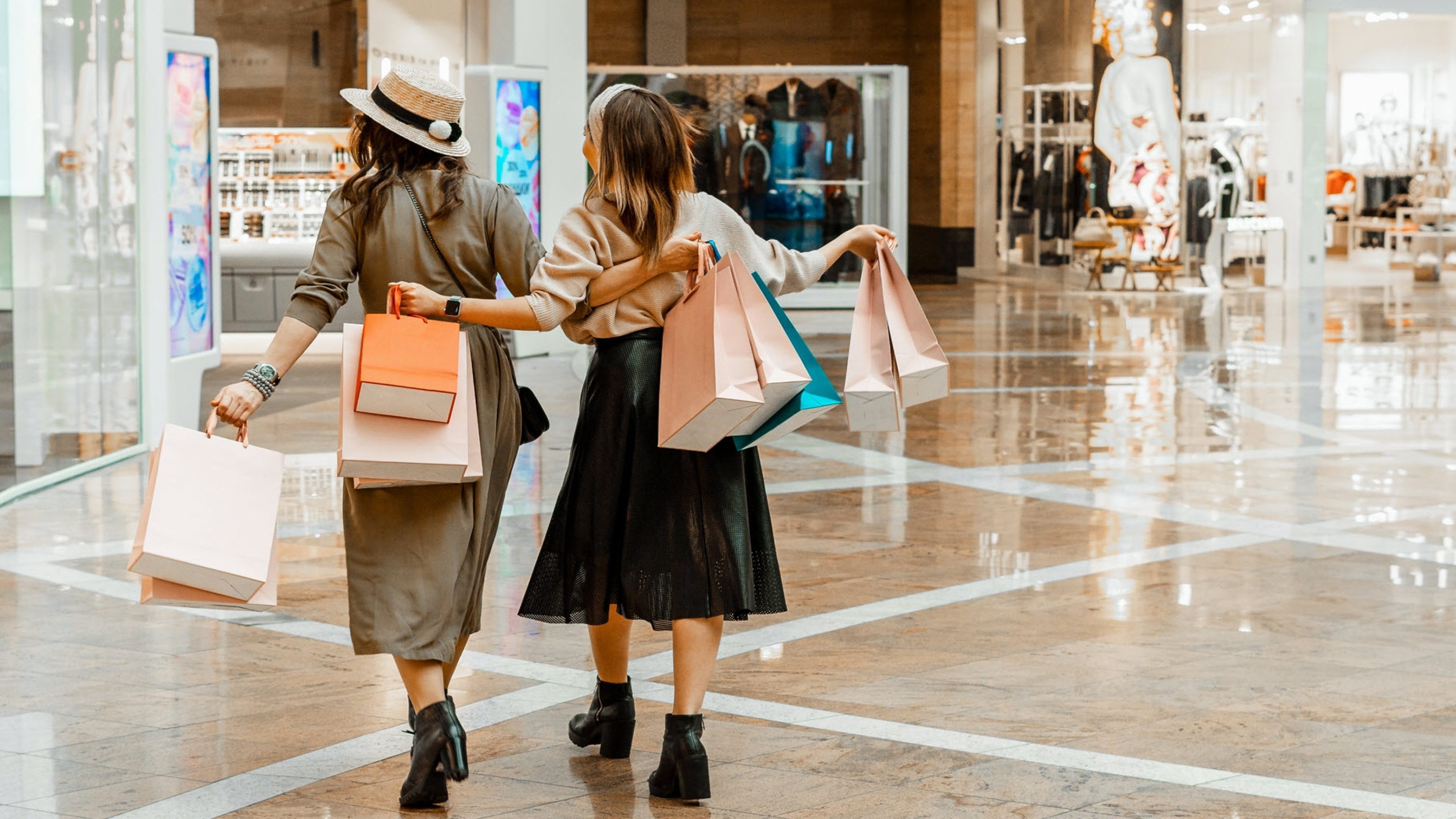 Two women with shopping bags in their hands in a shopping centre.
